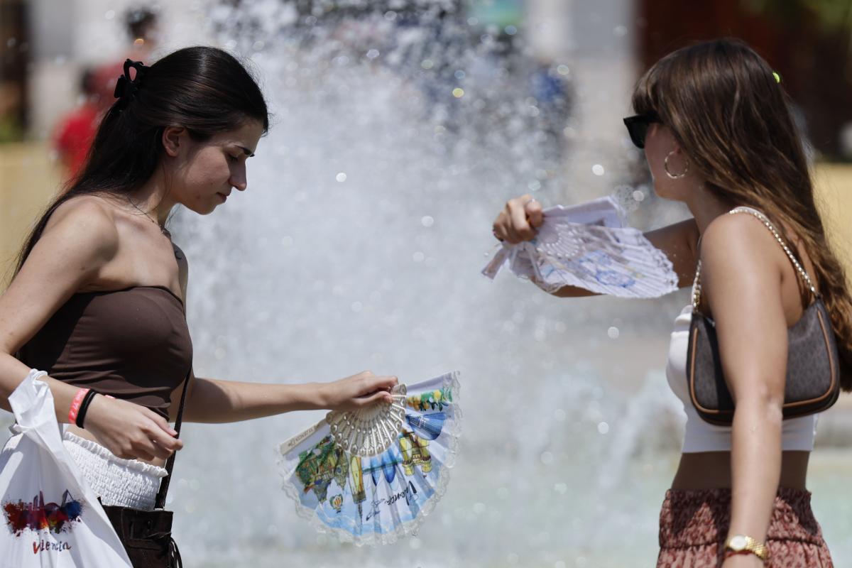 Dos mujeres se refrescan en el centro de València, durante la ola de calor de agosto de 2025.