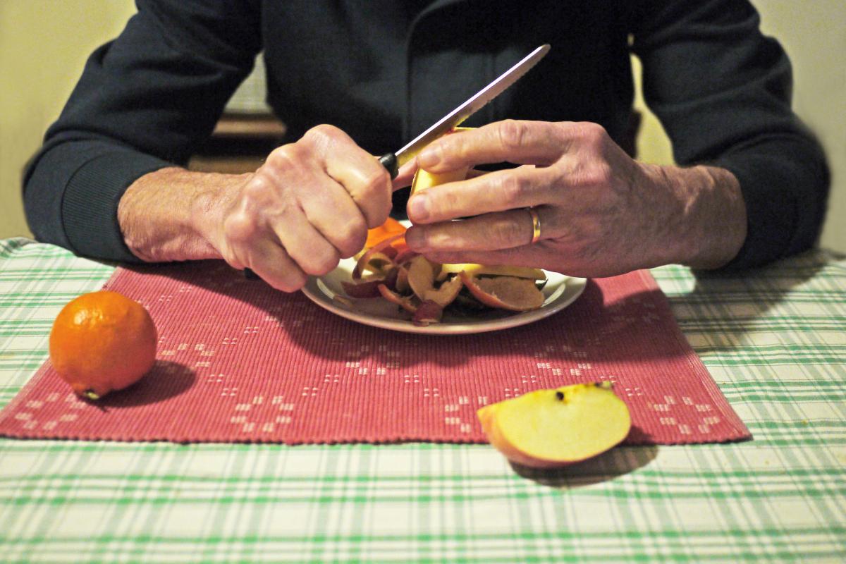 Una persona, pelando frutas en su cocina