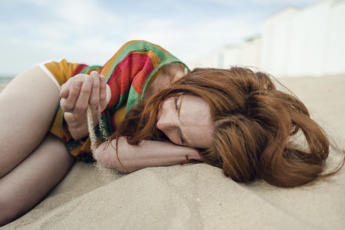 Una mujer tumbada en la arena de la playa.