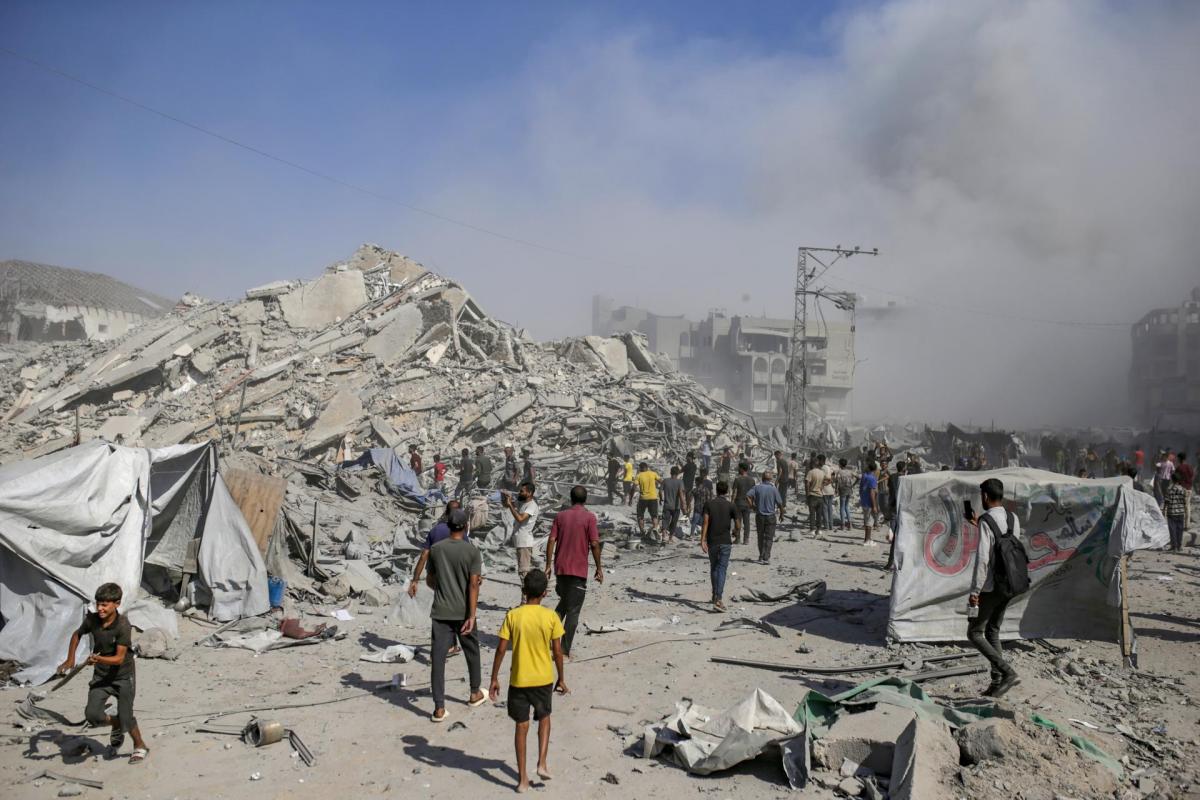 Palestinos caminan entre escombros mientras sale humo del edificio residencial al-Roya tras un ataque aéreo israelí en el oeste de la ciudad de Gaza, Franja de Gaza, el 8 de septiembre de 2025.