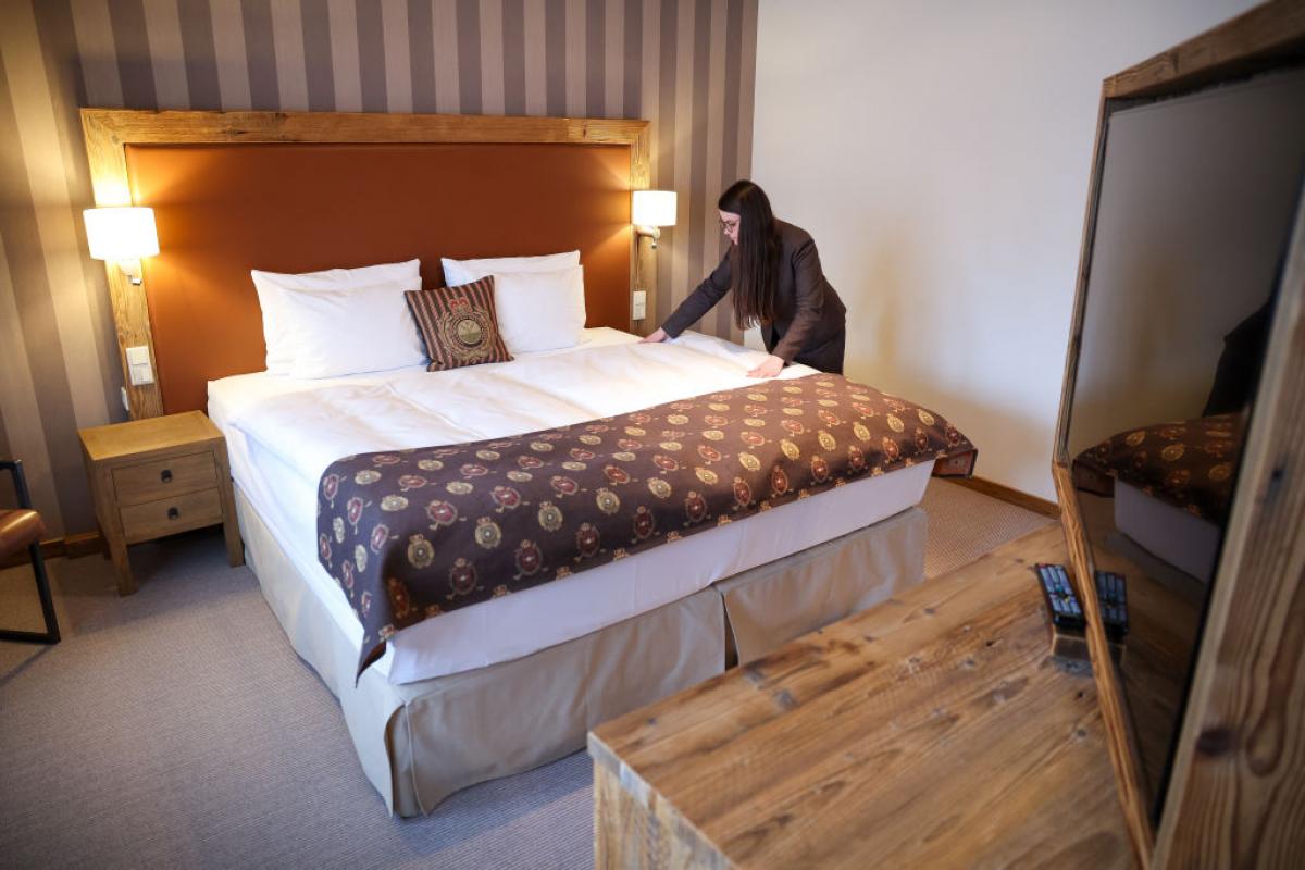 Habitación de hotel de cinco estrellas con cama doble preparada con textiles ligeros y sin edredón tradicional.