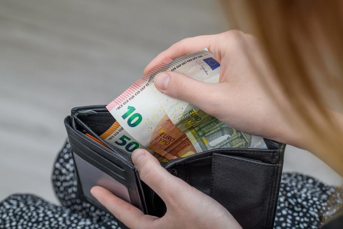 Mujer sacando billetes de euro de una cartera, símbolo de la recomendación del BCE de guardar efectivo en casa.