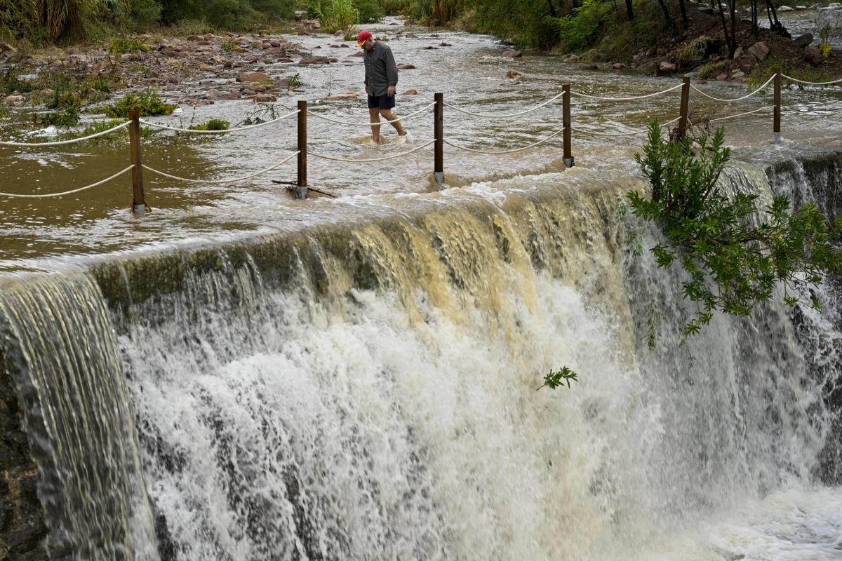 Un hombre cruza un badén inundable en Castellón.
