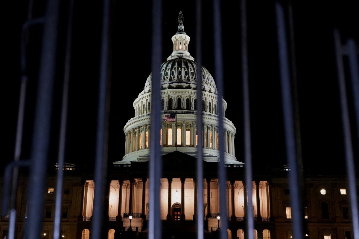 El Capitolio de Estados Unidos iluminada de noche, vista tras las rejas, antes del cierre de Gobierno en Washington.