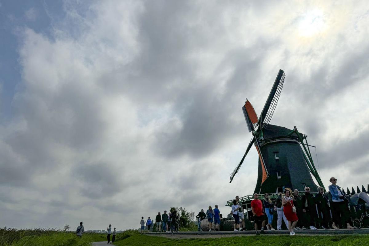 Turistas caminando frente a un molino de viento en Zaanse Schans, Holanda.