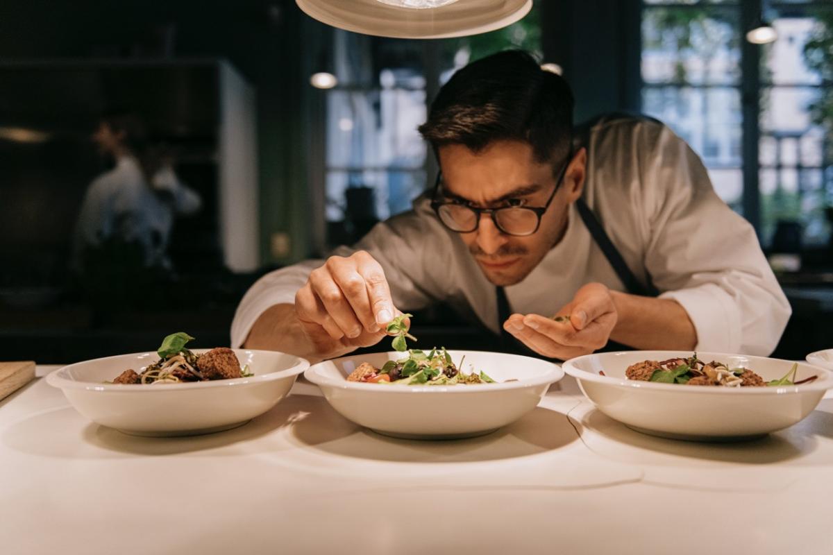 Chef preparando un plato con precisión en la cocina de un restaurante.