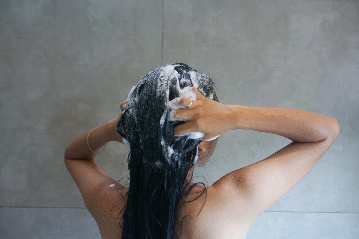 Una mujer, lavándose el pelo en la ducha.