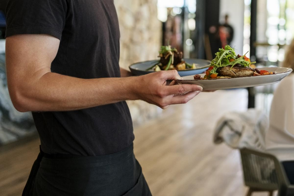 Camarero sirviendo platos a los clientes en un restaurante.