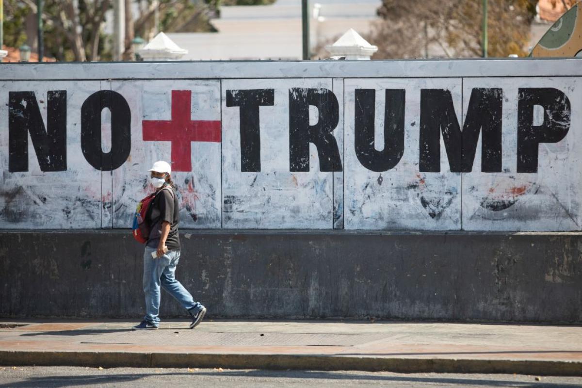 Una mujer camina junto a un grafiti contra el presidente estadounidense Donald Trump en Caracas.