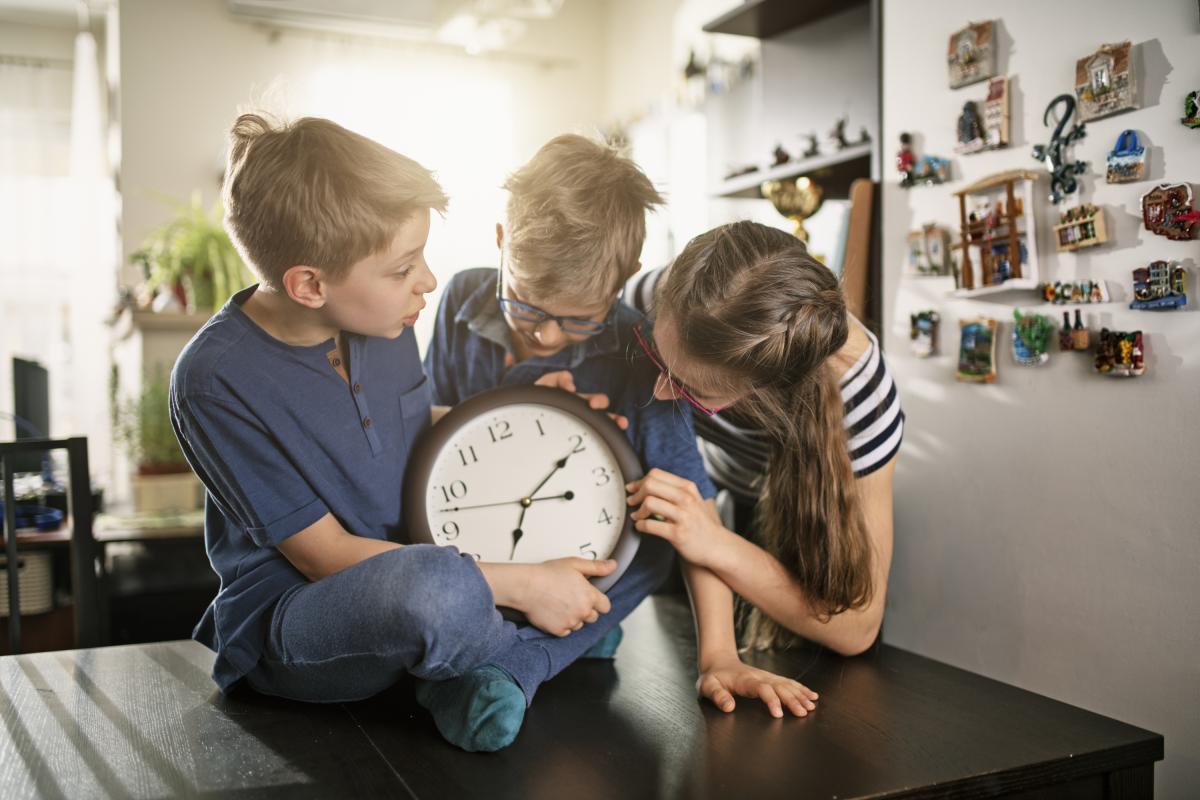Una familia se prepara para el cambio de hora cambiando las manijas del reloj.