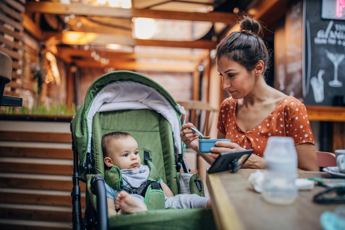 Mujer dando de comer a su hijo pequeño mientras está sentada en una cafetería.