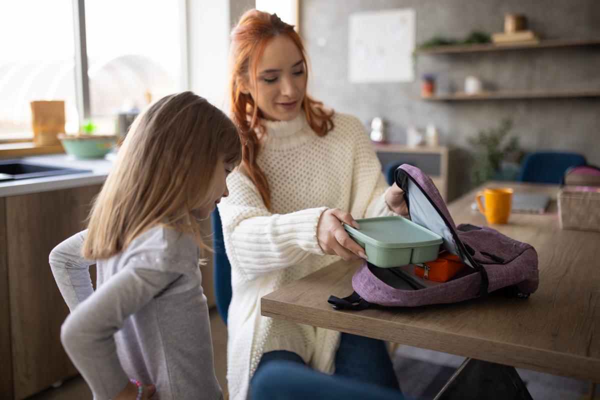 Niña pequeña en casa preparándose para ir al colegio con su madre.