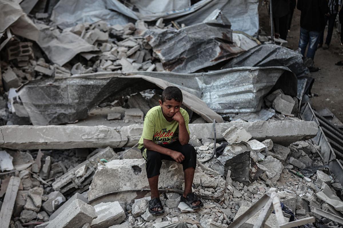 Un niño de Gaza, sentado sobre los escombros de un campo de refugiados destrozado por un ataque de Israel.