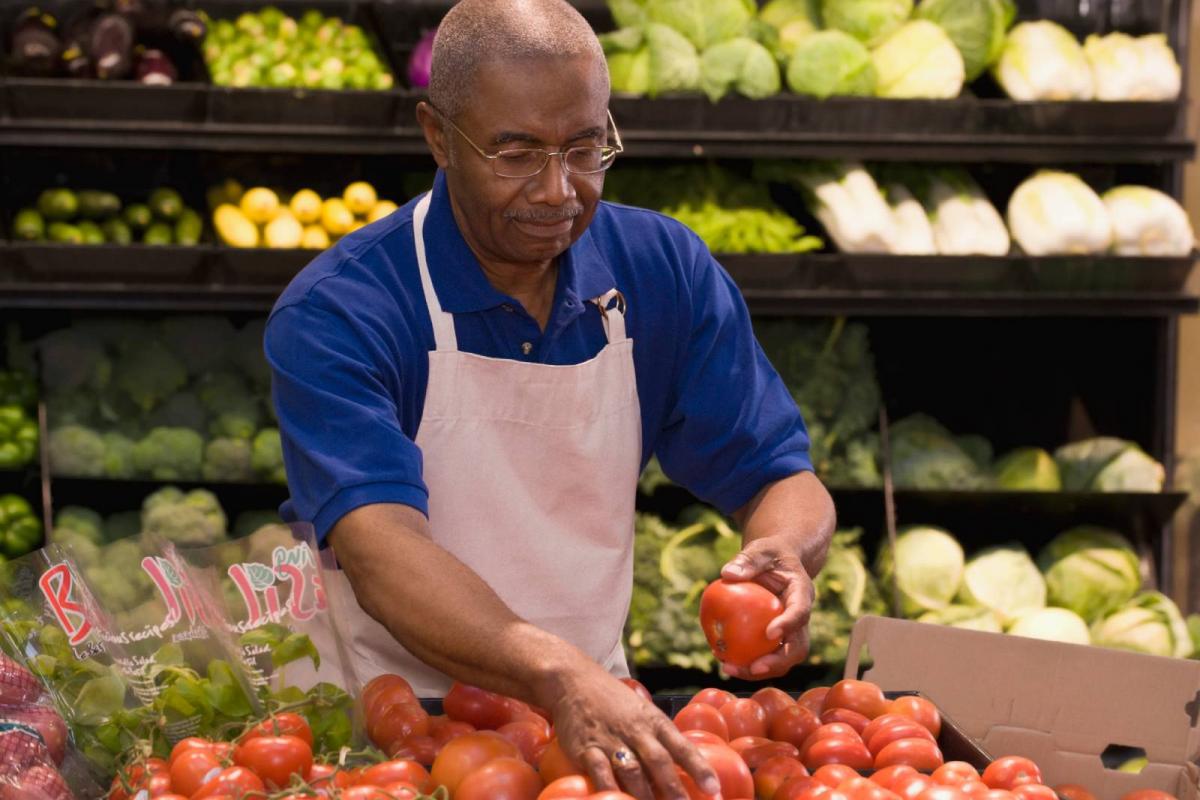 Hombre reponiendo verduras en el supermercado