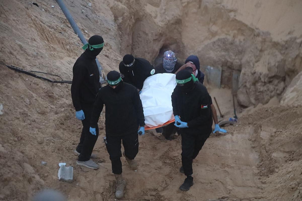 Encapuchados de las Brigadas Izz al-Din al-Qassam de Hamás sacan en camilla los restos de uno de los rehenes israelíes secuestrados.