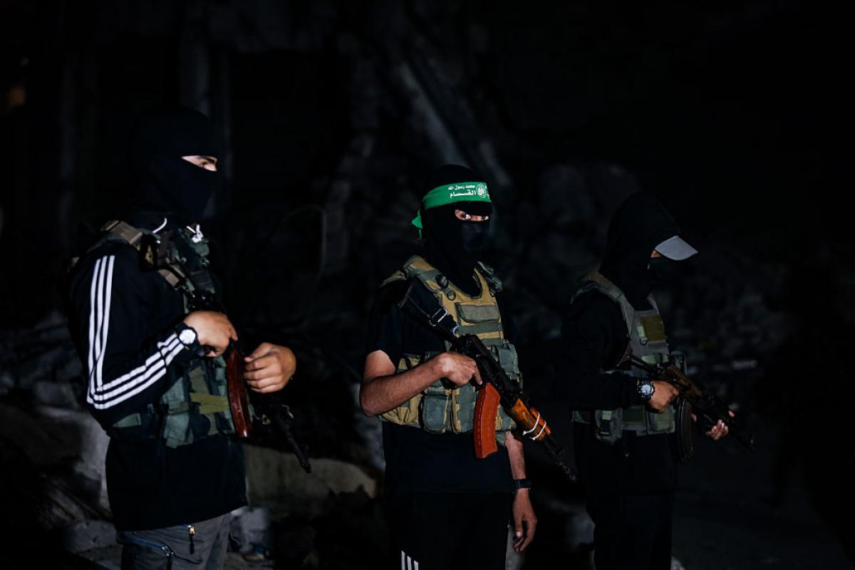 Miembros enmascarados de las Brigadas Ezzedin Al-Qassam, el brazo armado de Hamás, vigilan la entrega de cuerpos de rehenes a Cruz Roja, en mitas de la noche.