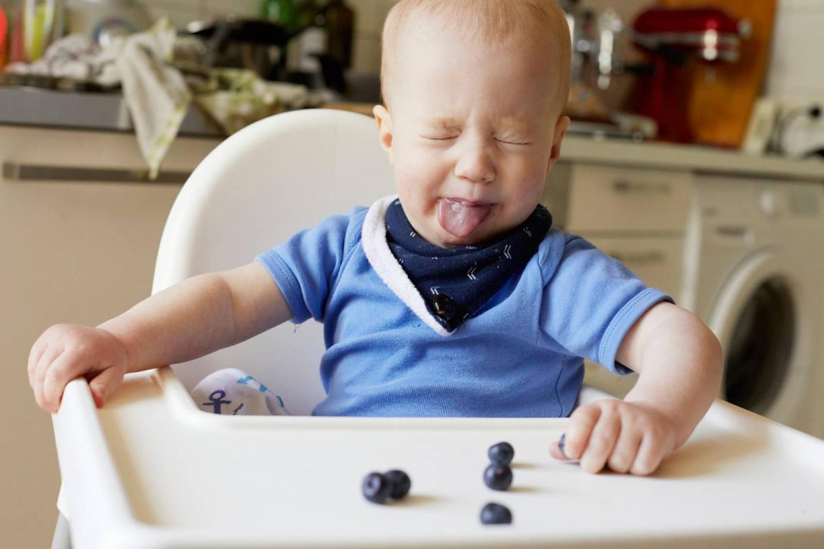 Bebé sacando la lengua a unos arándanos en la trona