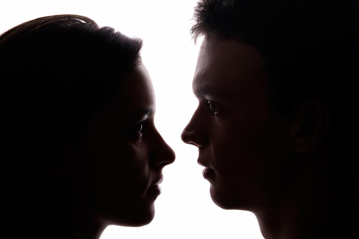 Una mujer y un hombre mirándose muy cerca con un fondo blanco.