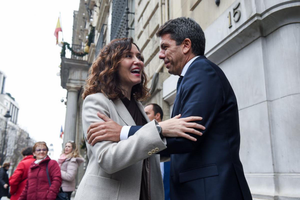 La presidenta de la Comunidad de Madrid, Isabel Díaz Ayuso, y el de la Generalitat Valenciana, Carlos Mazón, se abrazan a su llegada a la II Cumbre Empresarial bilateral, el 12 de diciembre de 2023, en Madrid.