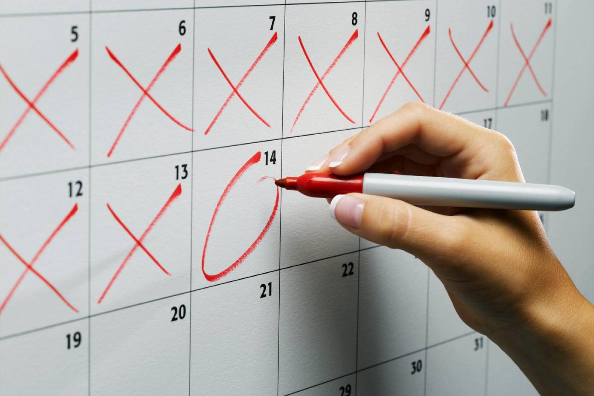 Mujer marcando un día en el calendario de pared, primer plano
