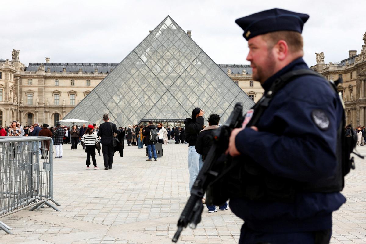 Un agente de la policía antidisturbios francesa patrulla cerca de la pirámide de cristal del Museo del Louvre, tras el robo de joyas, el 27 de octubre de 2025.