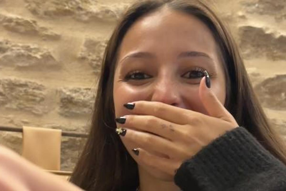 Joven riéndose con la mano en la boca durante una comida en un restaurante, escena del vídeo viral de TikTok sobre cómo se comen las zamburiñas.