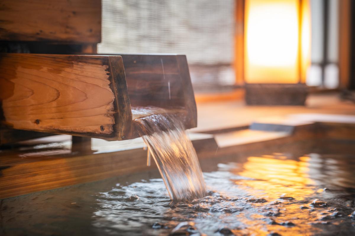 Un grifo de madera vierte agua caliente en un baño termal.