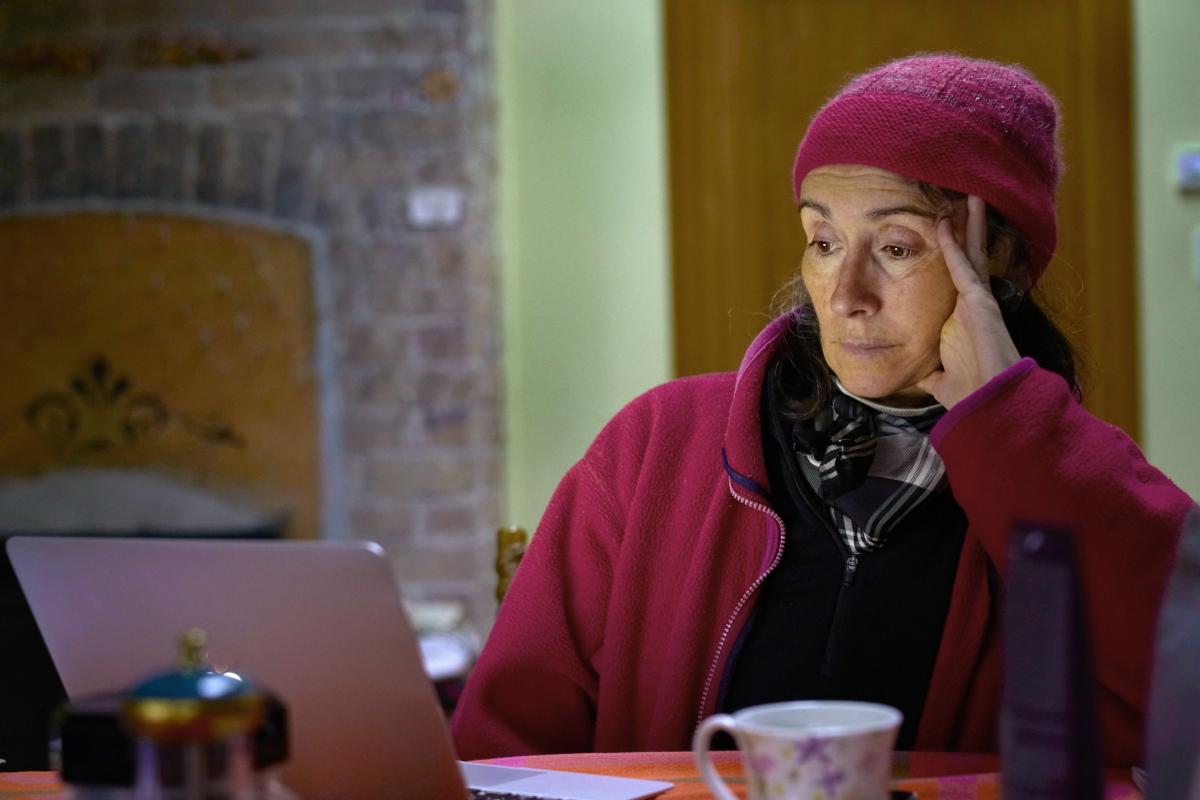 Una señora próxima a la edad de jubilación se relaja en casa frente a su ordenador portátil, conectada al resto del mundo por Internet.