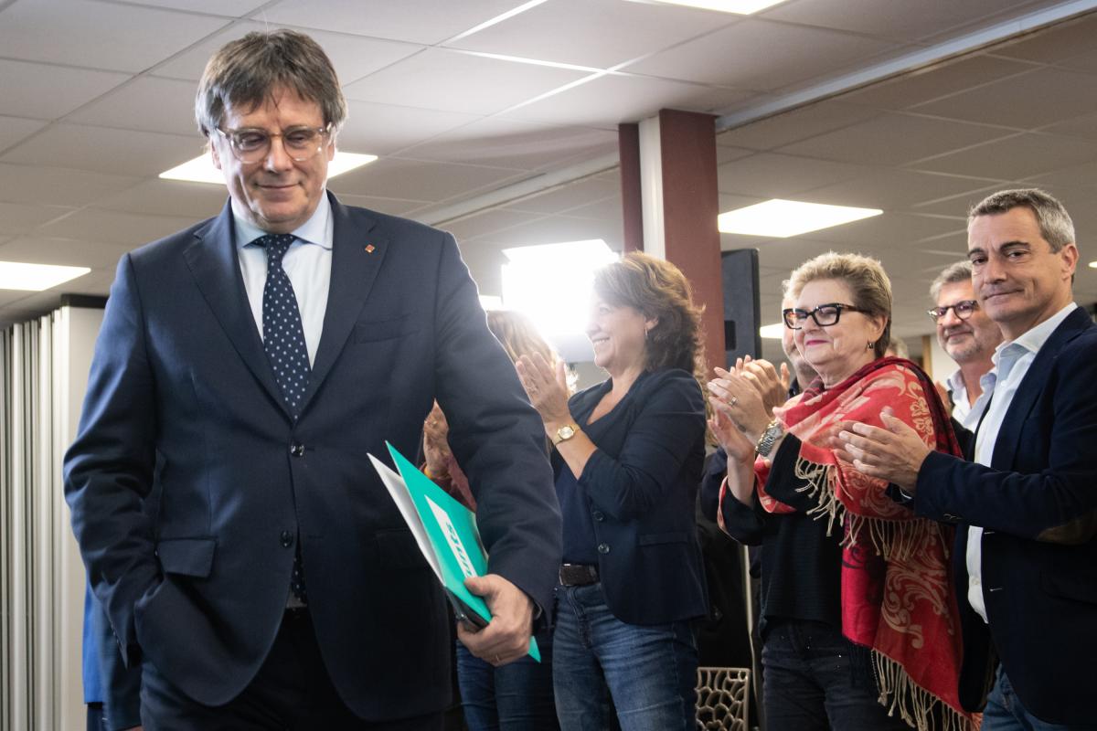 Carles Puigdemont sonriente, aparecer con una carpeta bajo el brazo durante un acto