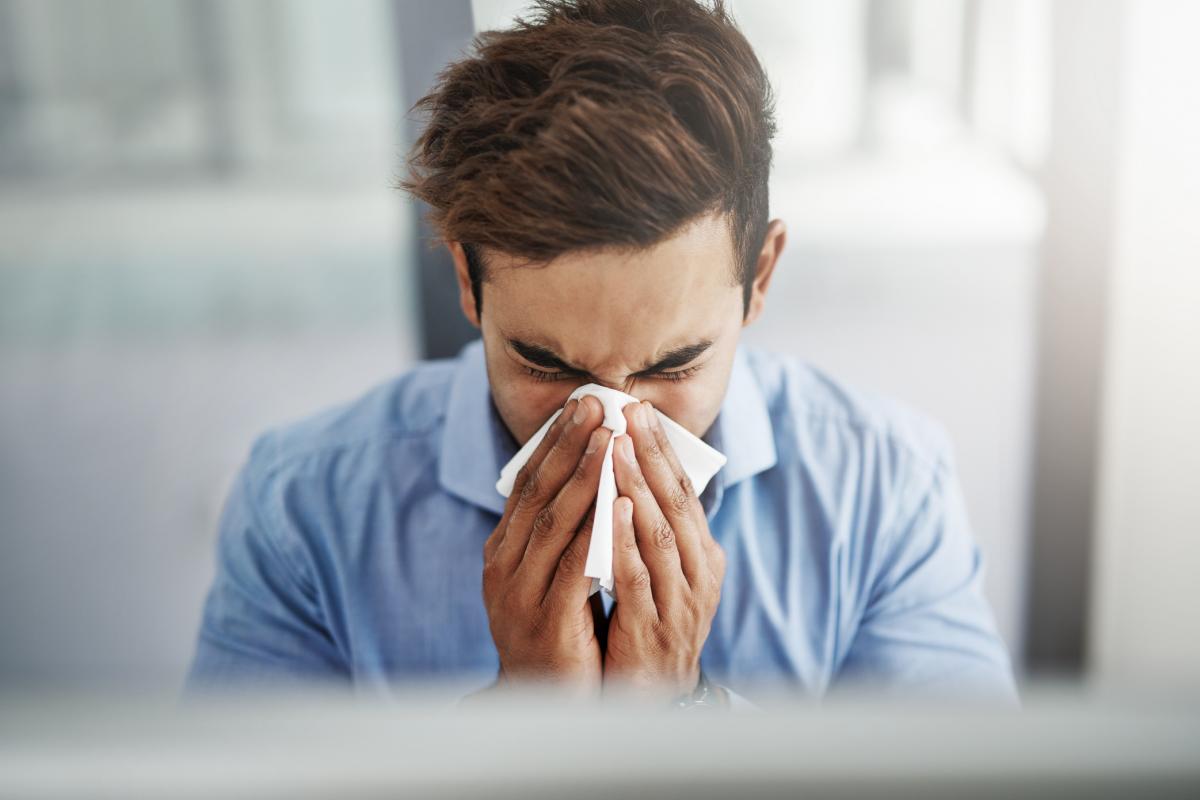 Una persona, sonándose en una oficina.