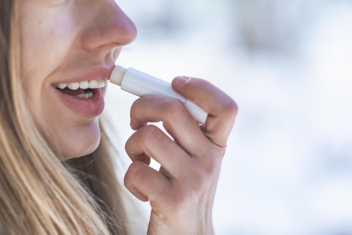 Una mujer aplicándose bálsamo labial en un día de frío