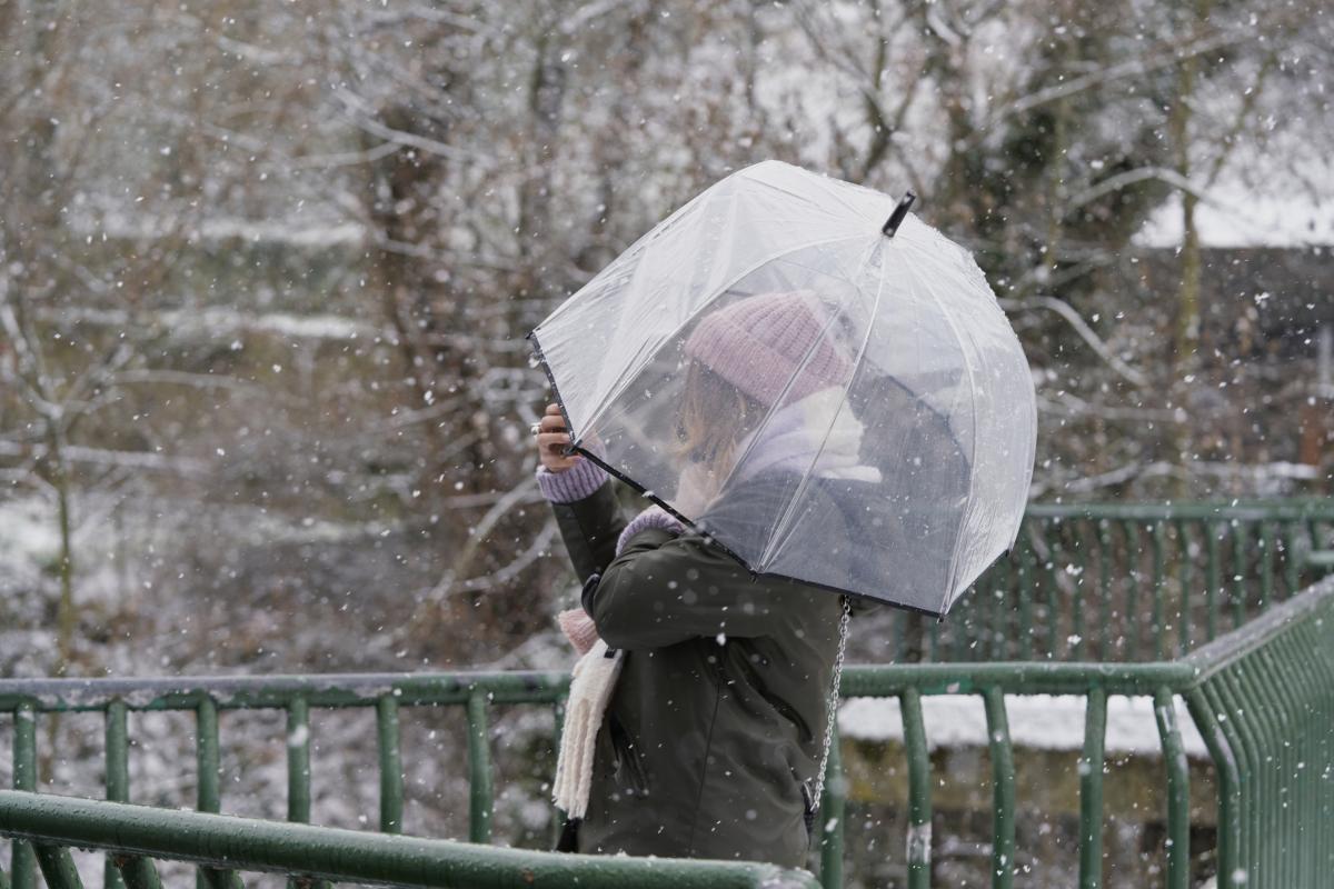 Una mujer cubriéndose con su paraguas de la nieve.