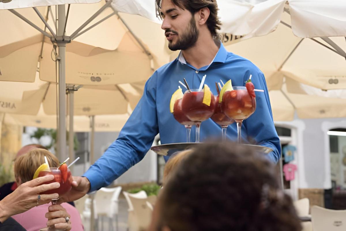 Un camarero sirviendo sangría a una mesa llena de turistas