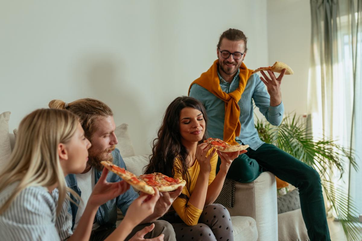 Un grupo de amigos comen pizza en casa.