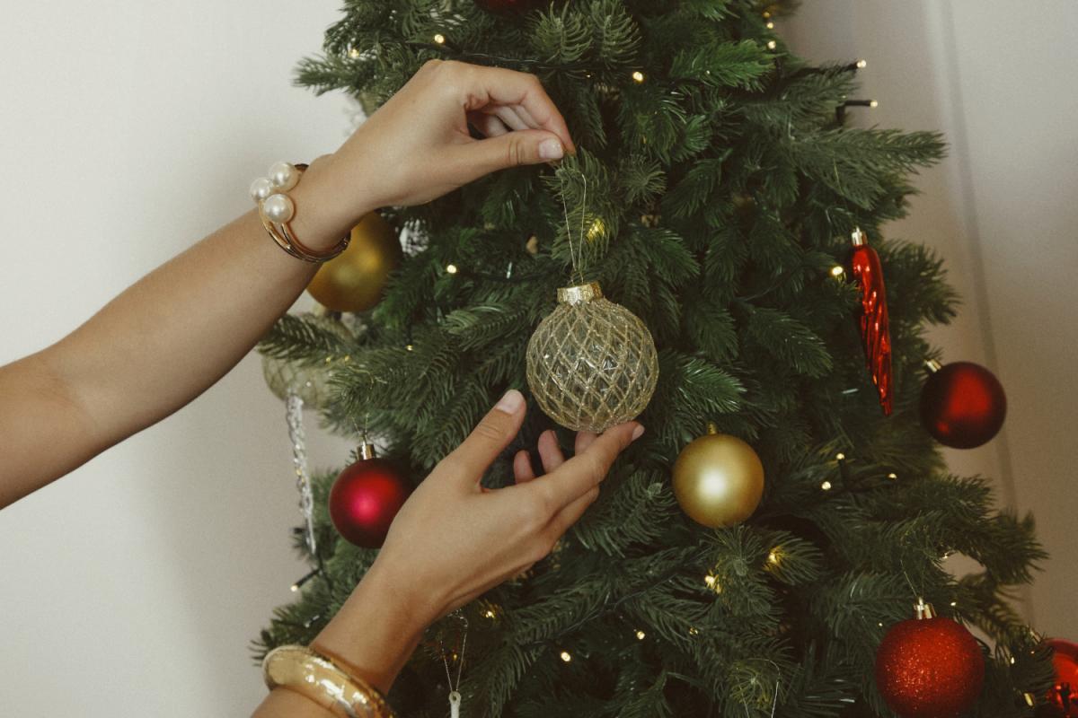 Una mujer colocando una bola en un árbol de Navidad