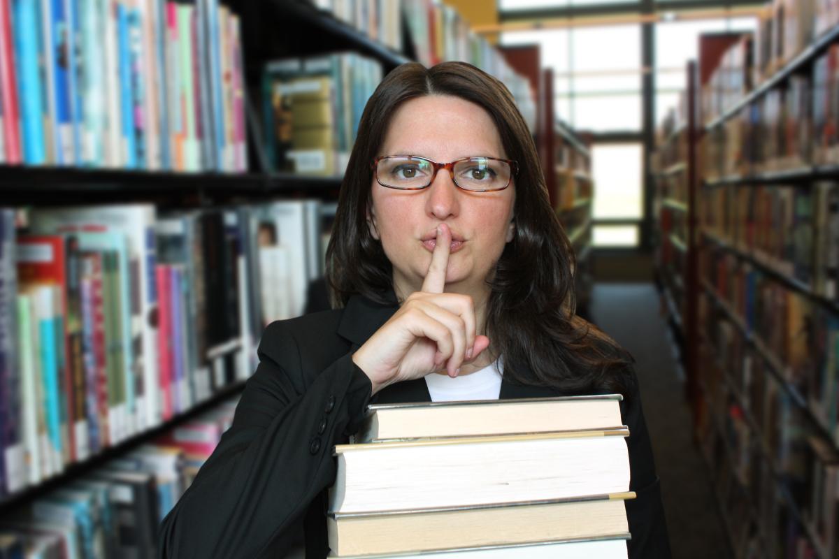 Una mujer pidiendo silencio en una biblioteca.