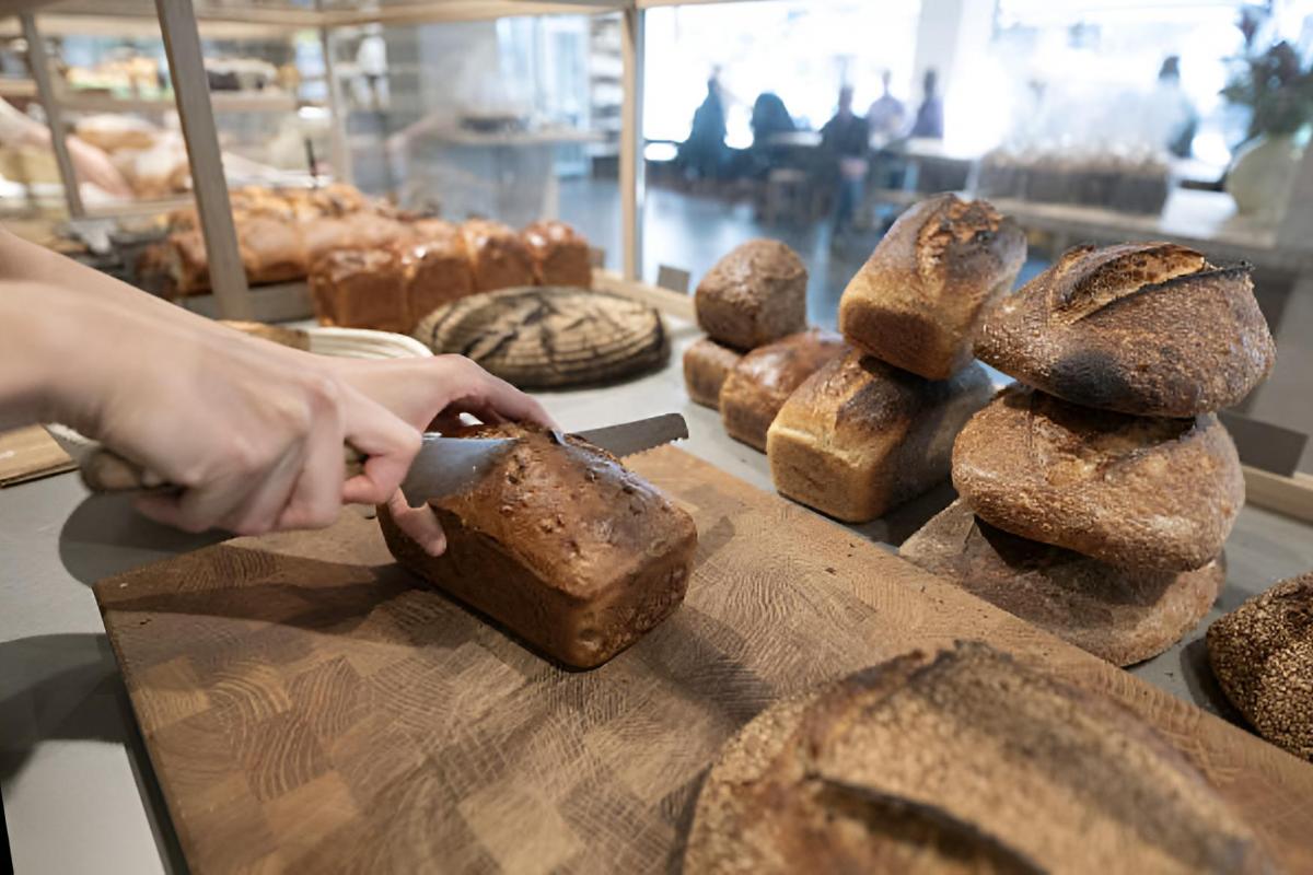 Un empleado cortando pan recién hecho para venderlo