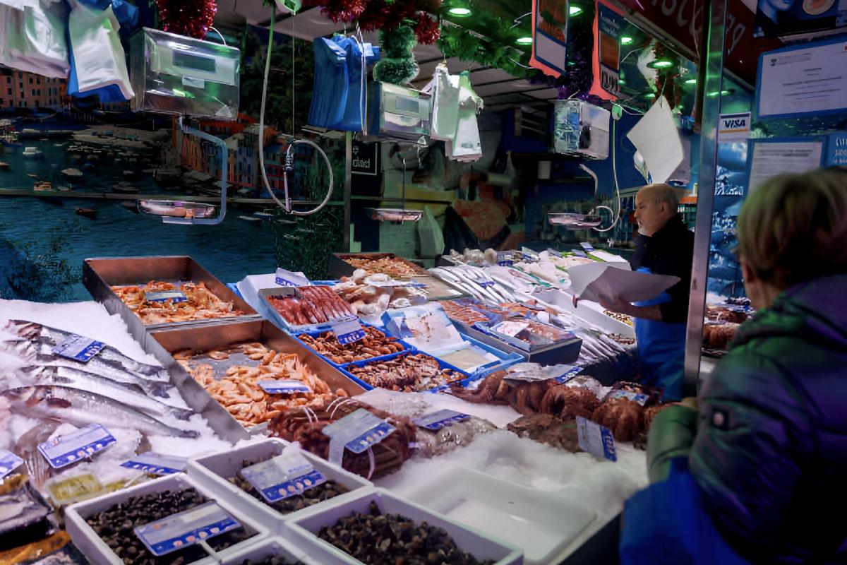 Un pescadero atendiendo a una clienta en un mercado local.