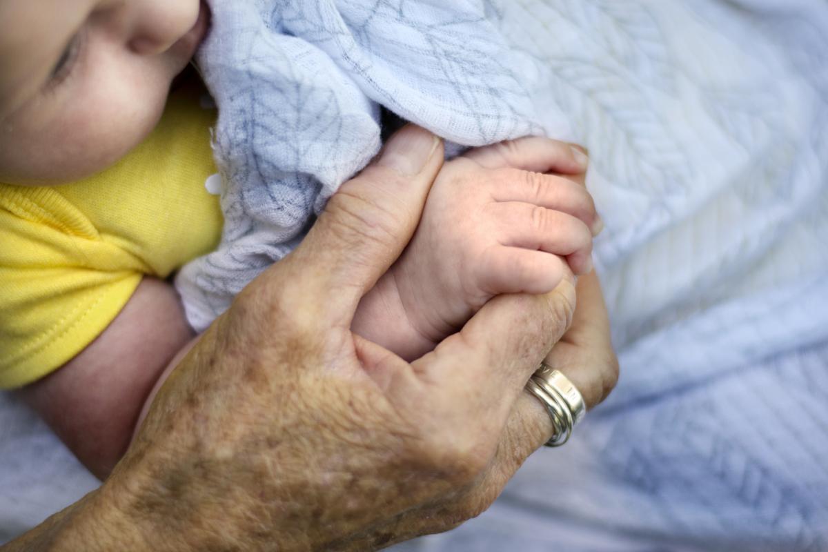 Primer plano de un bebé sosteniendo las manos de su abuela