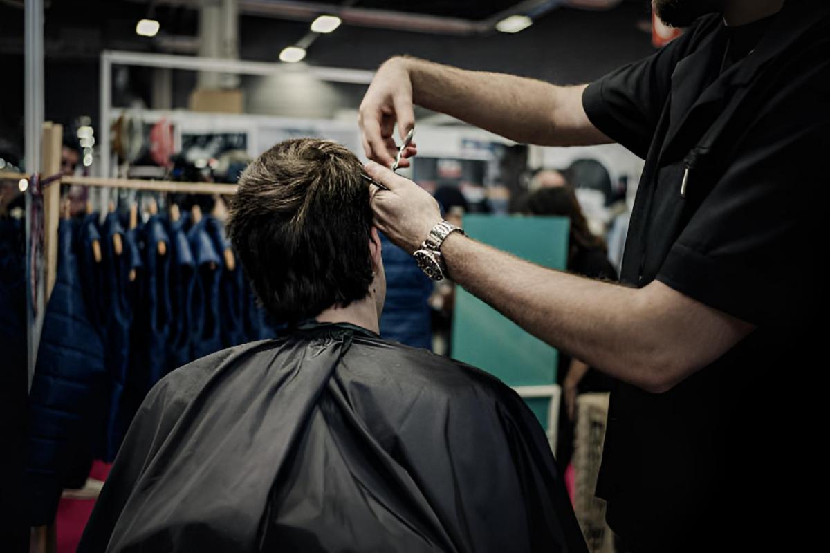 Un barbero cortando el pelo a un cliente en una foto de archivo