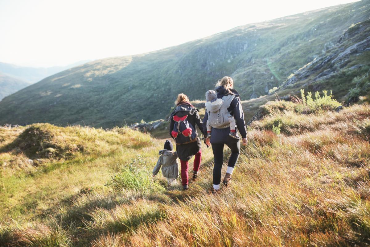 Familia, de espaldas, caminando por las montañas de Noruega.