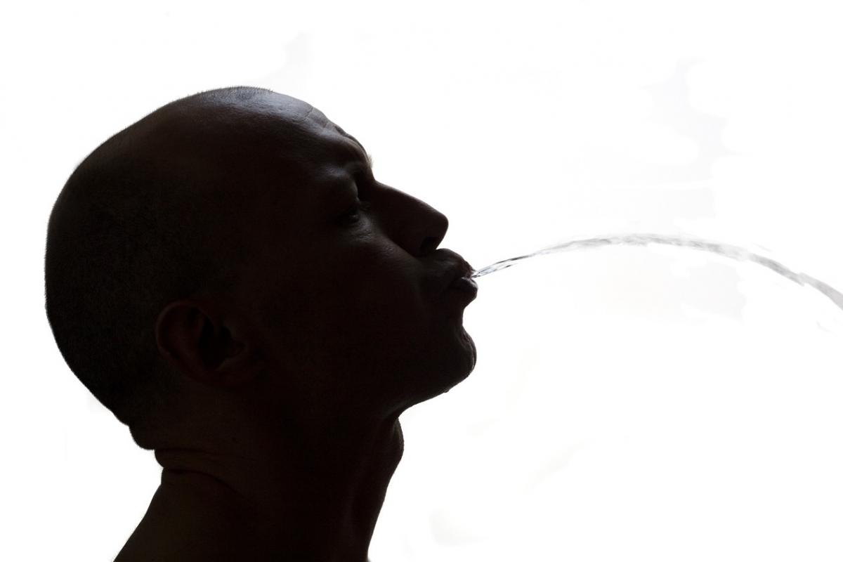 La silueta de un hombre escupiendo en la calle.