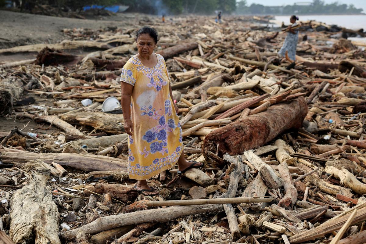 Una mujer mira desolada un terreno lleno troncos varados en la orilla tras las inundaciones y los deslizamientos de tierra, en Padang (Indonesia), el 30 de noviembre de 2025.