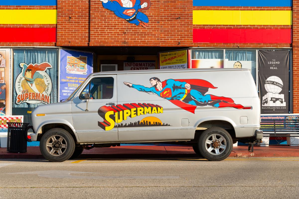 Una furgoneta con un Superman dibujado enfrente de una tienda de artículos del superhéroe