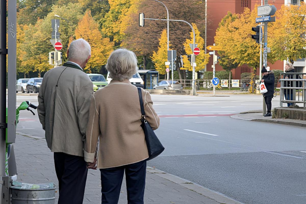 Una pareja de jubilados dándose la mano en la calle