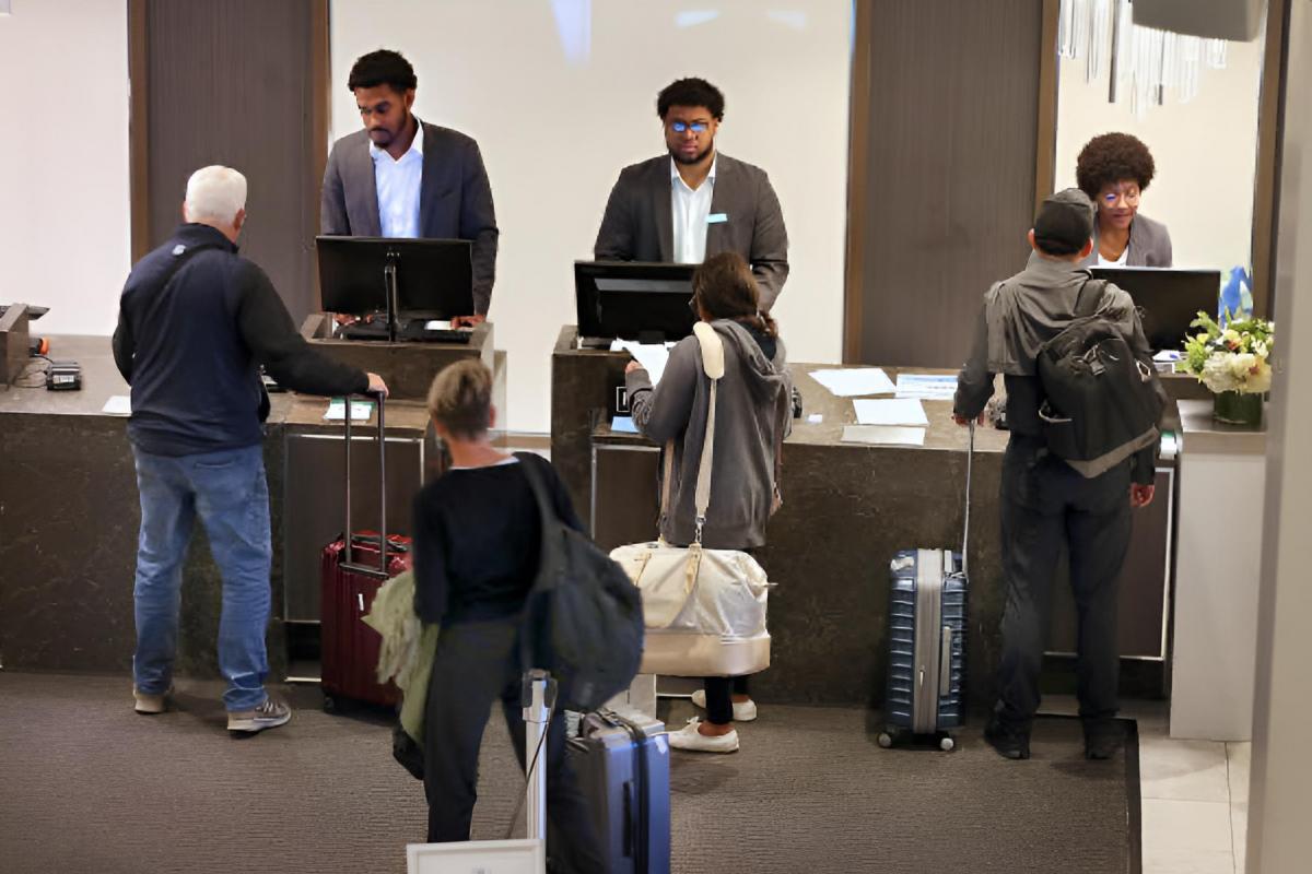 Varios huéspedes esperando a ser atendidos en la recepción de un hotel