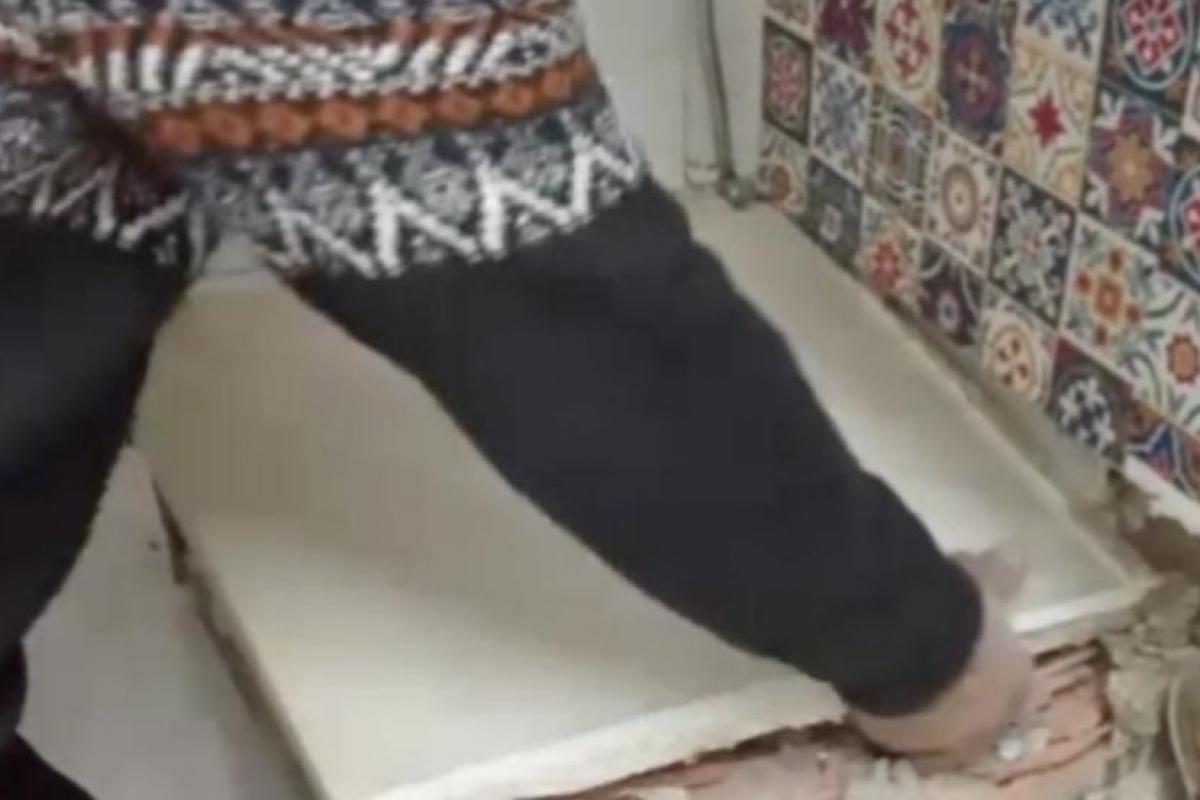 Persona retirando una encimera antigua y revelando una losa de mármol escondida en una reforma de cocina.