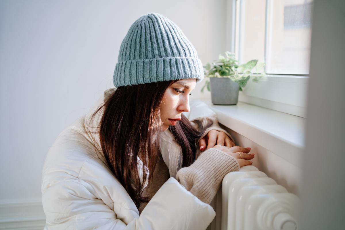 Una mujer con las manos en el radiador.