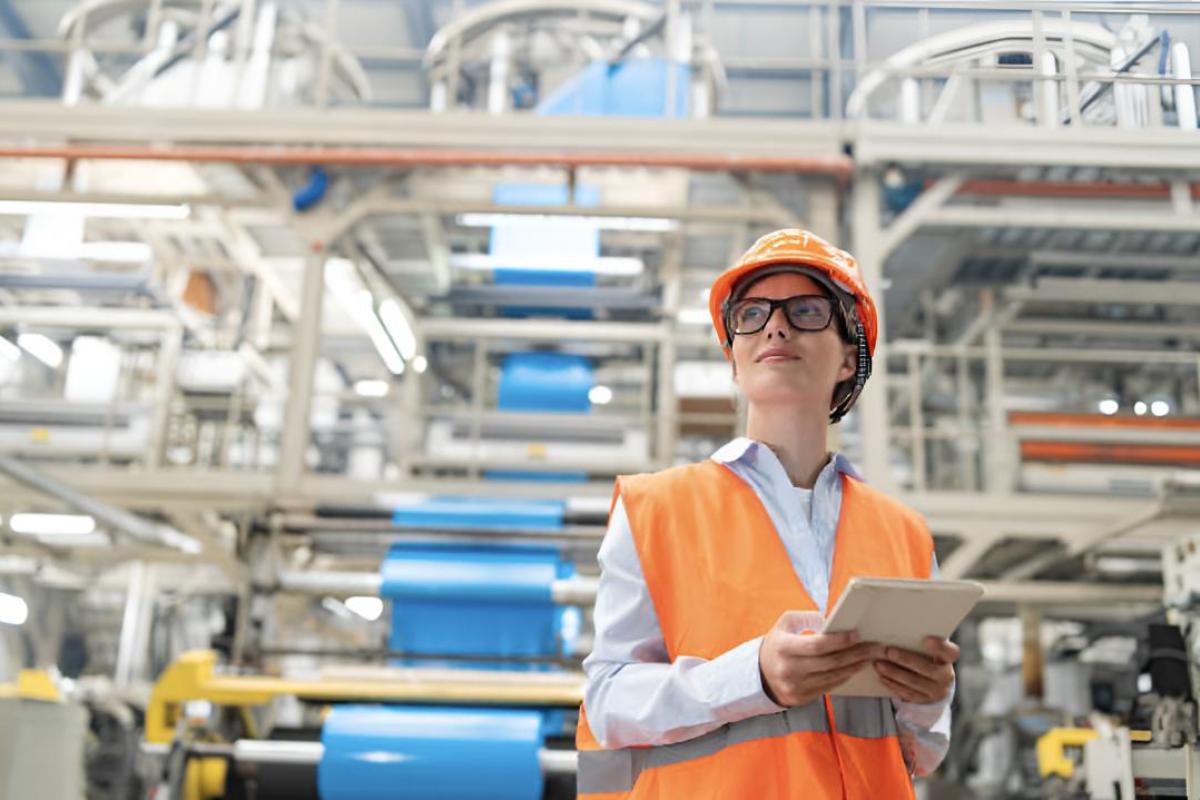Una ingeniera que viste un chaleco y un casco de color naranja brillante
