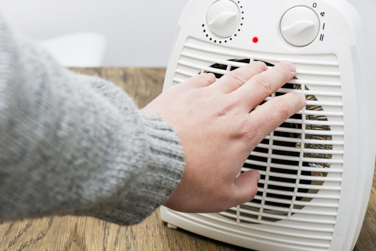 Una persona se calienta con un ventilador de radiador